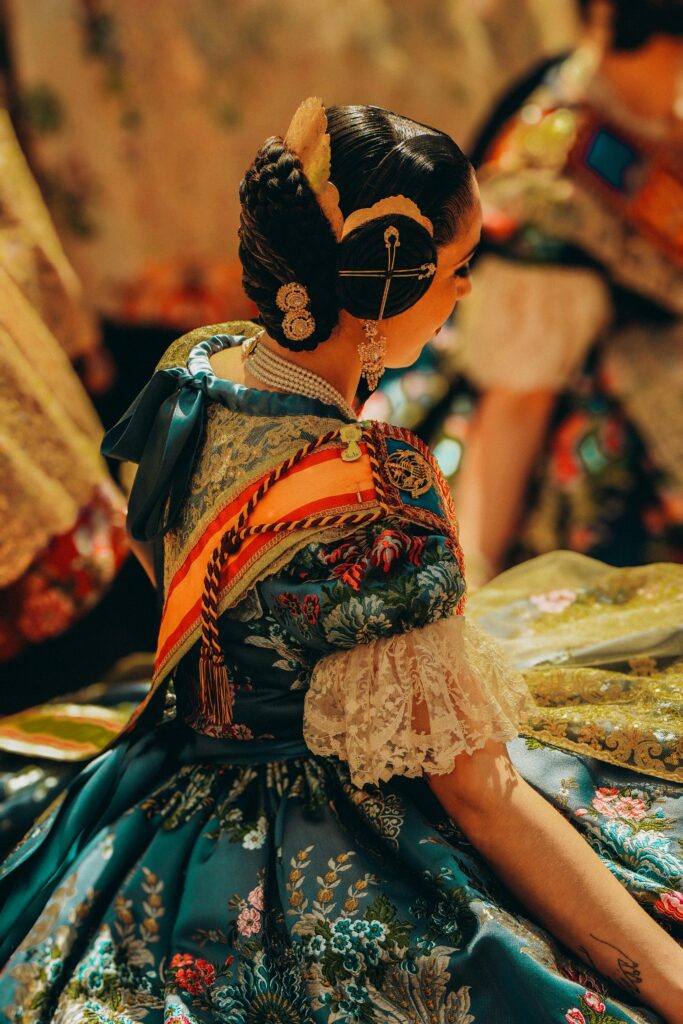 Close-up of a fallera in traditional dress during Valencia's festivity, showcasing intricate embroidery and vibrant colors.